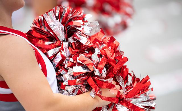 A cheerleader holding red and silver pompoms.