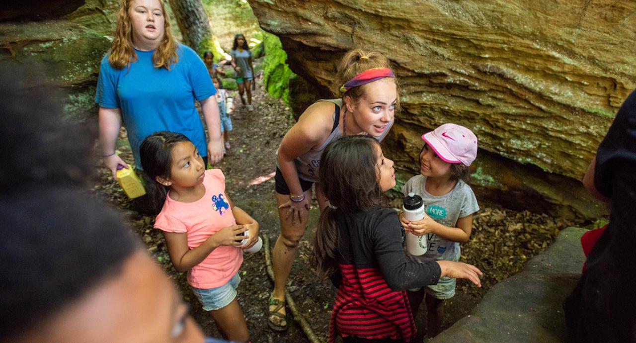 An Ohio State student talks to two children during an outdoors excursion.